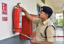 फायर सेफ्टी निरीक्षण के दौरान भवन में लगे अग्निशामक यंत्र की जांच करते पुलिस अधिकारी की तस्वीर।
