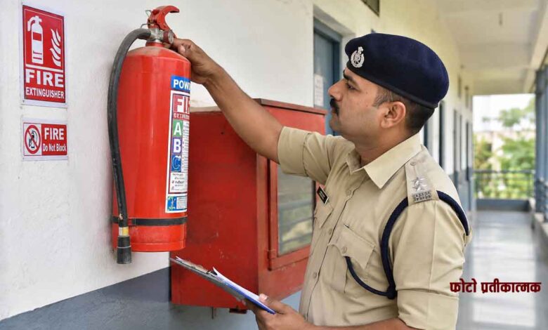 फायर सेफ्टी निरीक्षण के दौरान भवन में लगे अग्निशामक यंत्र की जांच करते पुलिस अधिकारी की तस्वीर।