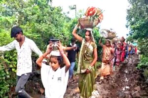 दुकली की खराब सड़क से कीचड़ में होकर गुजरती महिलाएं
